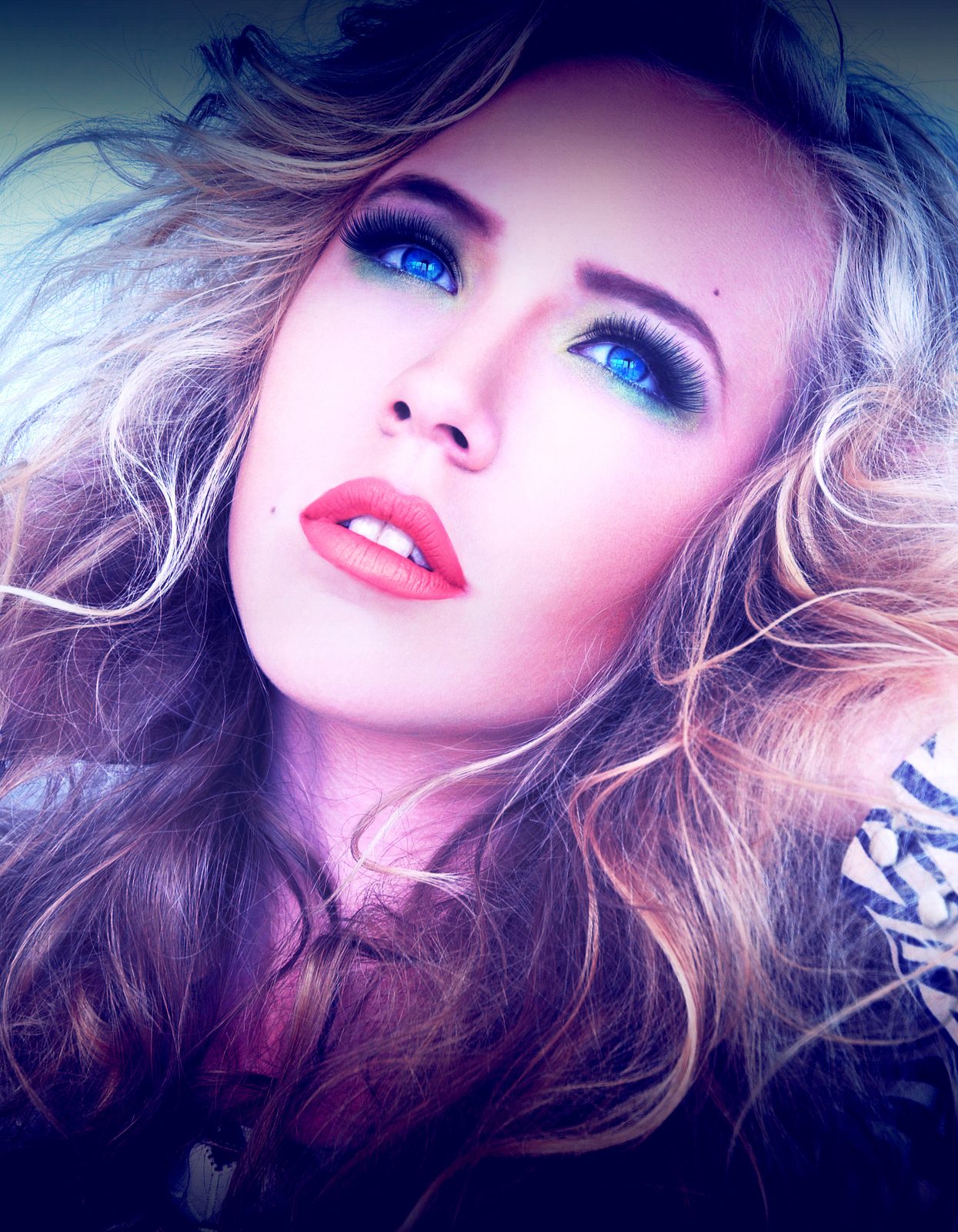 Close-up beauty portrait of a blonde model with tousled curls, bright blue eyeshadow and coral lips, a zebra-print garment at her shoulder