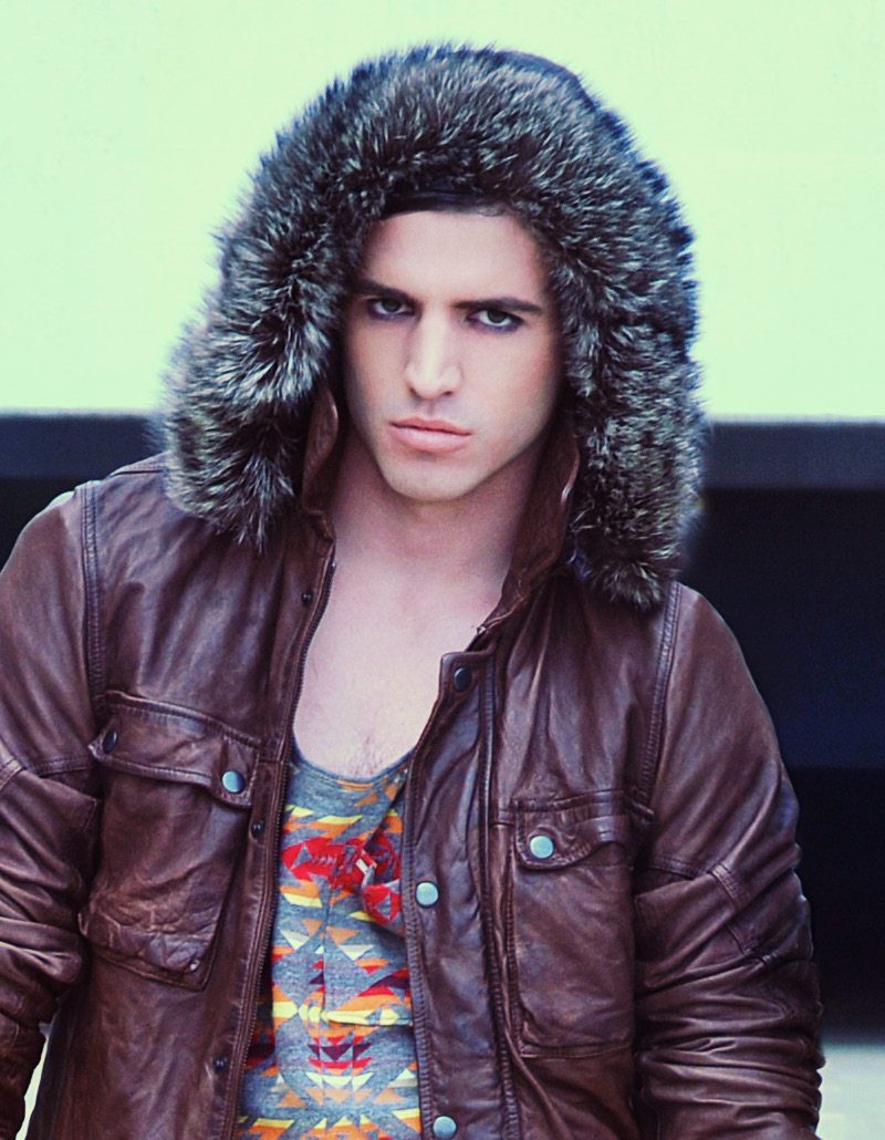 Male model in a fur-trimmed hooded leather jacket over a printed tank