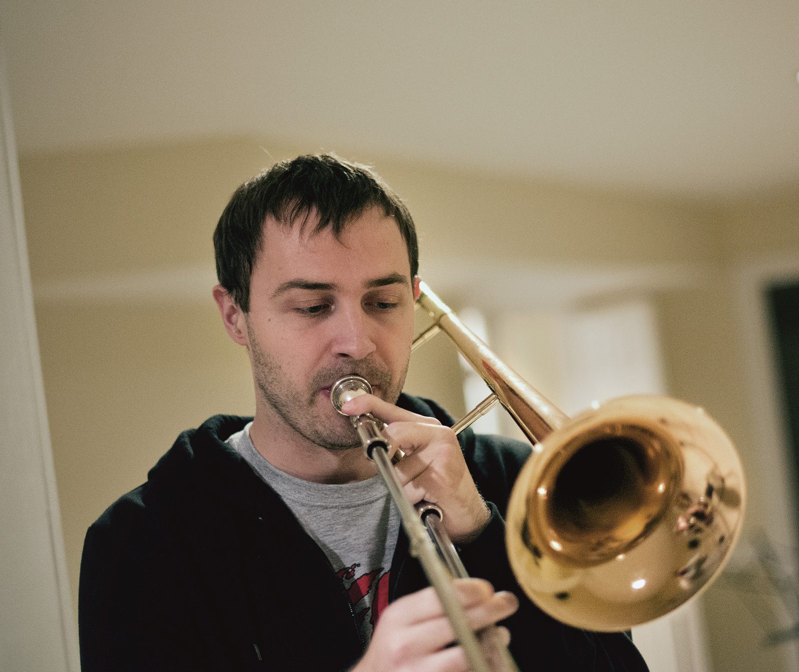 A Kill Lincoln horn player in a black hoodie blowing a trombone