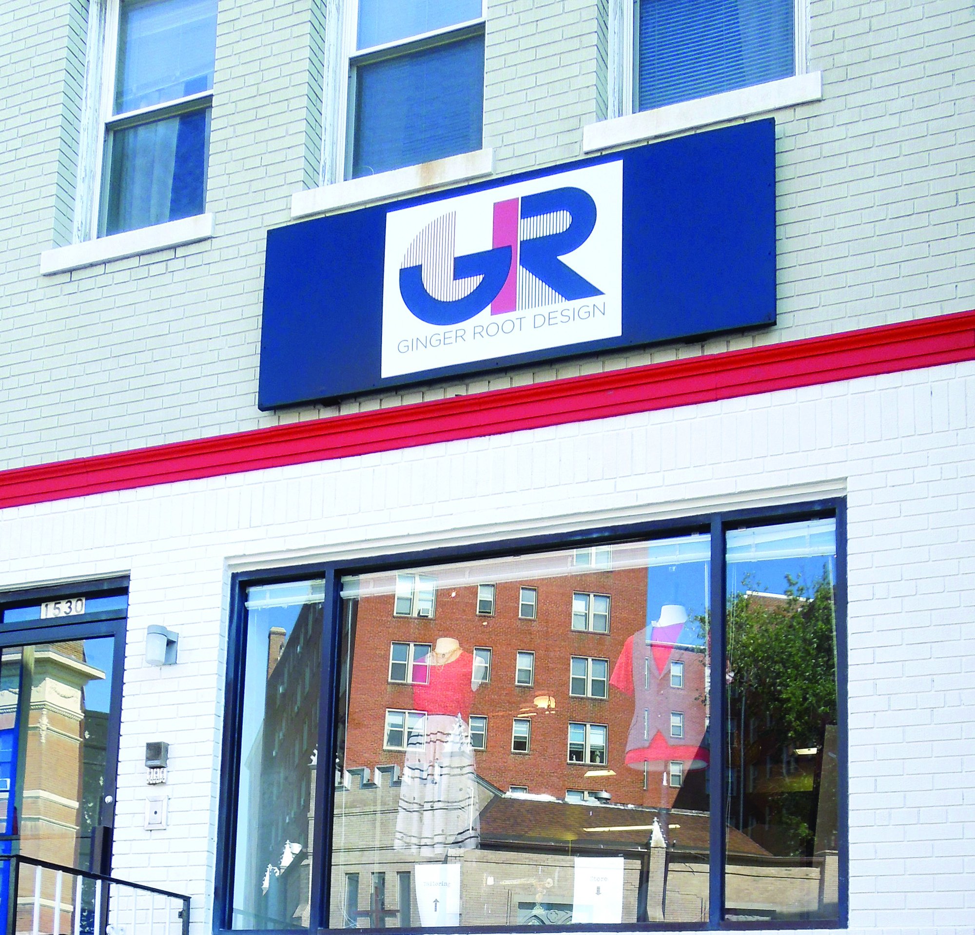 Ginger Root Design boutique storefront with a blue GR sign above a large display window on a white brick building