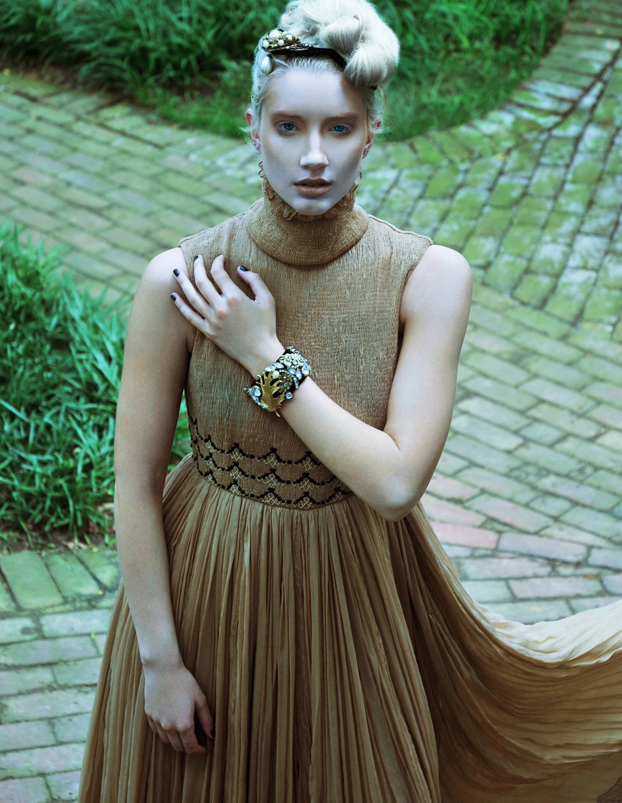 Model with a platinum updo in a high-neck pleated gown with a beaded collar and statement cuff