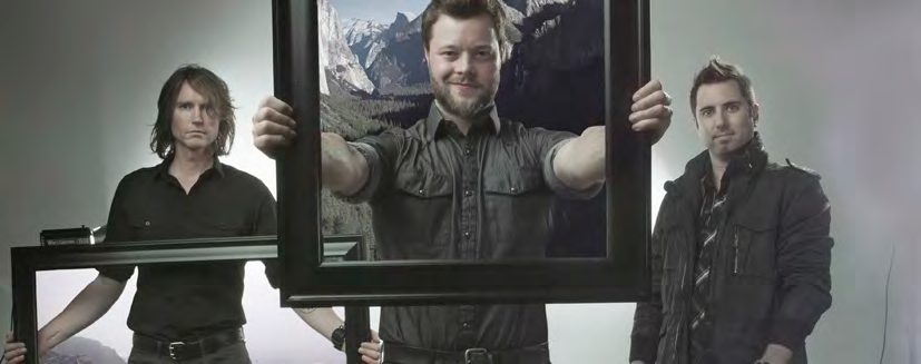Three members of the band Oedipus, the middle one holding an empty picture frame in front of a mountain backdrop