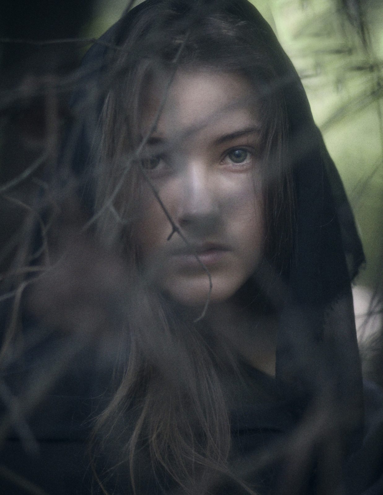 Close portrait of the model in a black hood, hair falling across her face