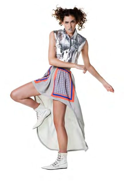 Model in a silver metallic vest and a long grey skirt with a patterned scarf panel, posing in white boots