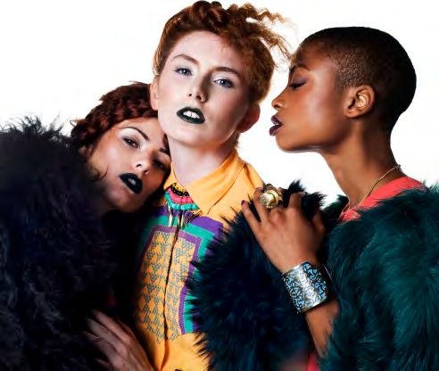 Three models with dark lipstick huddled together in faux fur, a bright geometric print shirt and a statement cuff