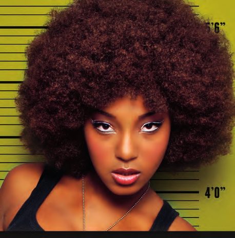 Mug shot of a model with a voluminous afro and bright white eyeliner against a chartreuse height chart