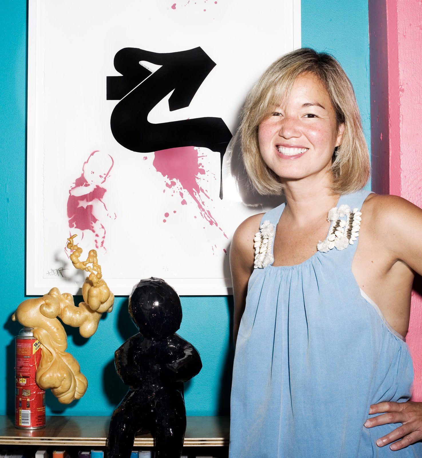 Philippa Hughes smiling beside a large black and red street art piece painted on her apartment wall