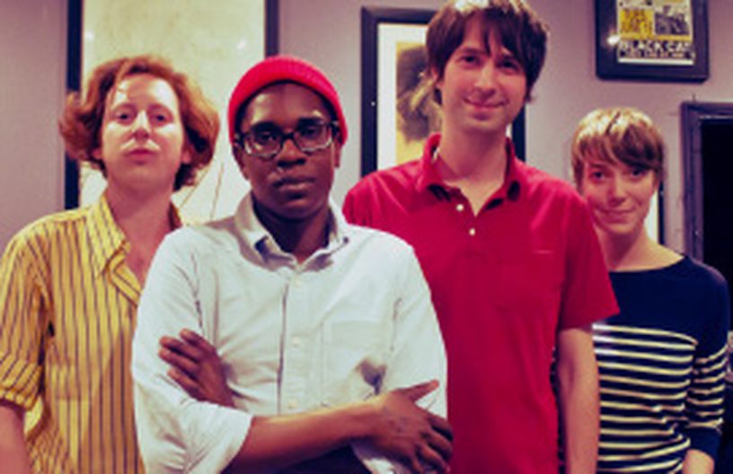The four members of Ra Ra Rasputin standing arms crossed in a bar, one in a red beanie and glasses