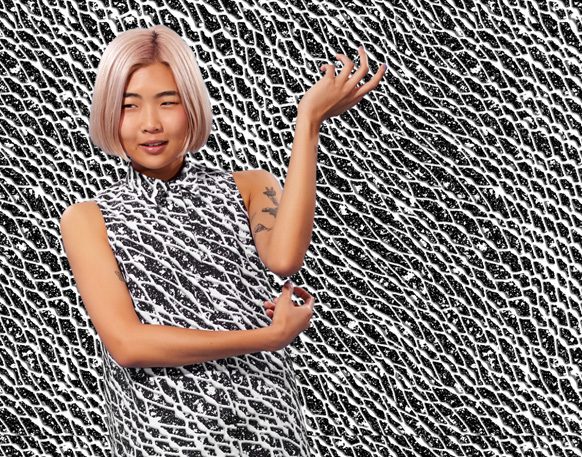 Model in a black and white mesh print sleeveless dress posed against a matching optical print backdrop
