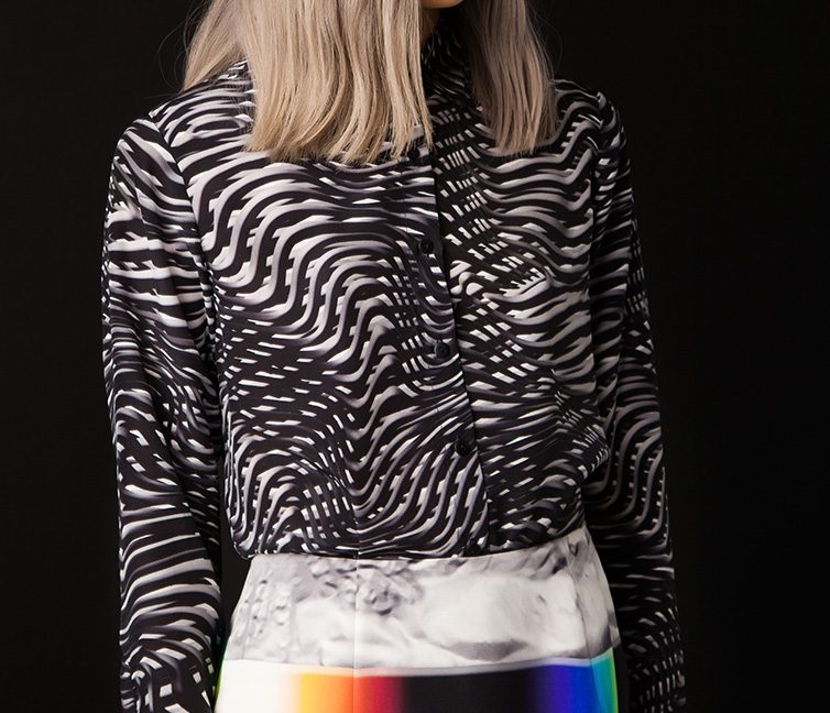Model from behind in a black and white wavy zebra style printed top over a prismatic print skirt