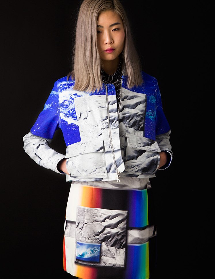 Model in a cobalt and white glacier print jacket with a prismatic stripe skirt against a black background