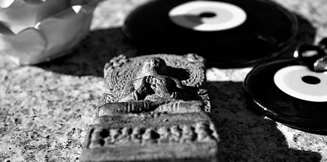 A small carved stone figure beside evil eye charms, in black and white