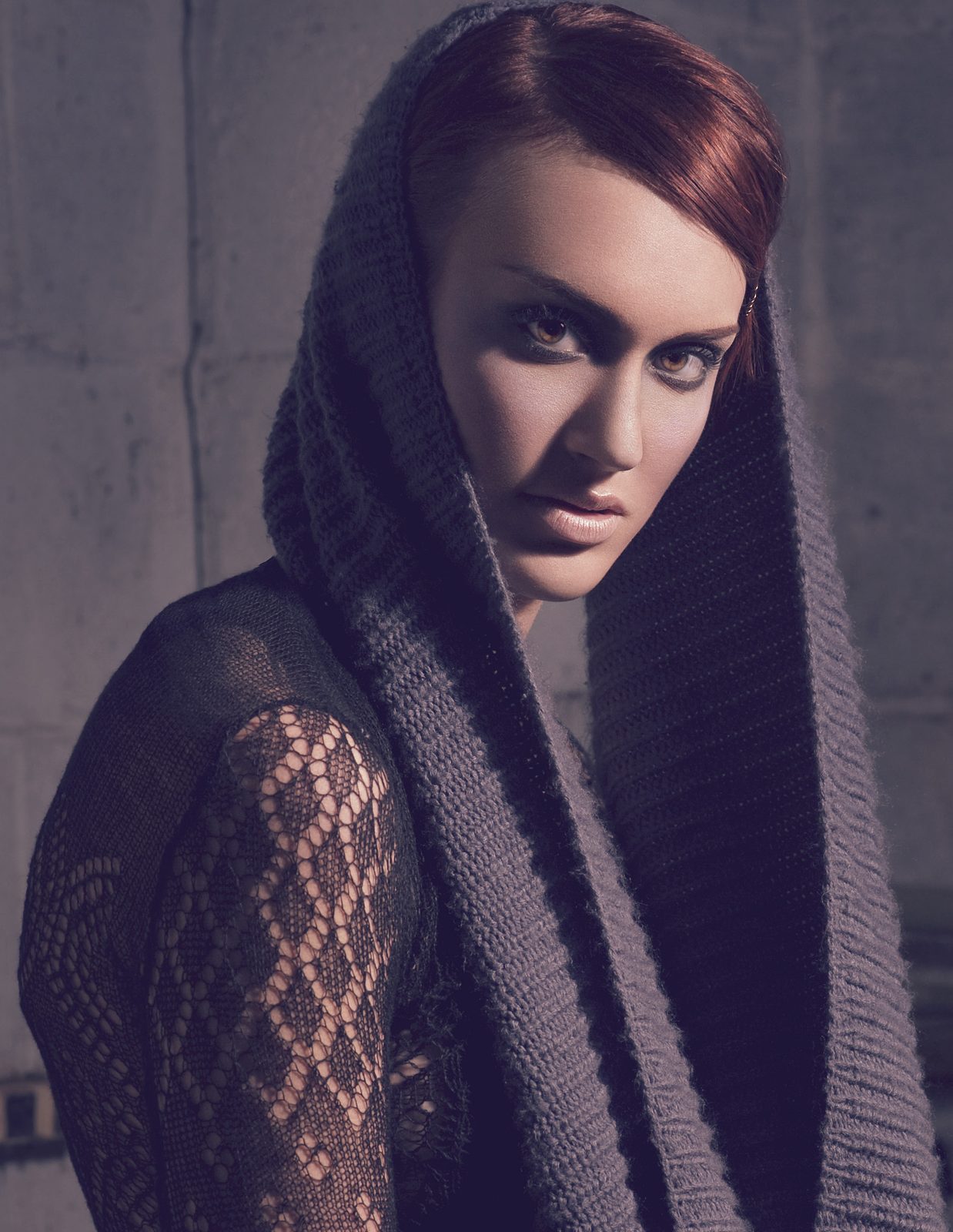 Model in a chunky grey knit hood over a sheer black lace shirt